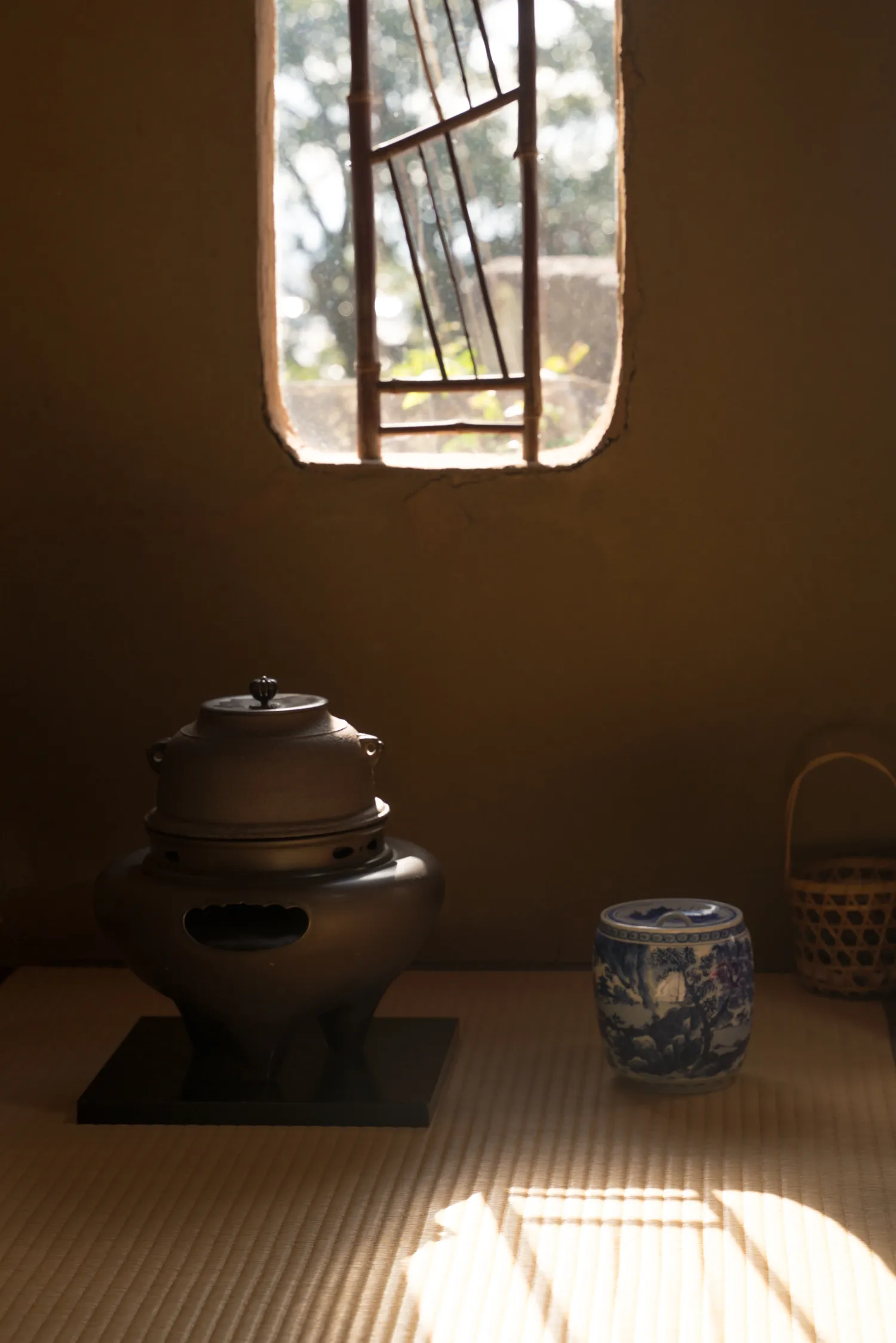 An iron kettle on the brazier in an old Japanese tea room, window light across the tatami